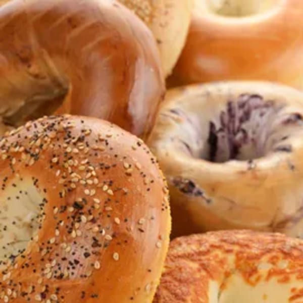 Assortment of New York Bagel Company bagels, including poppy seed, sesame, and blueberry varieties.