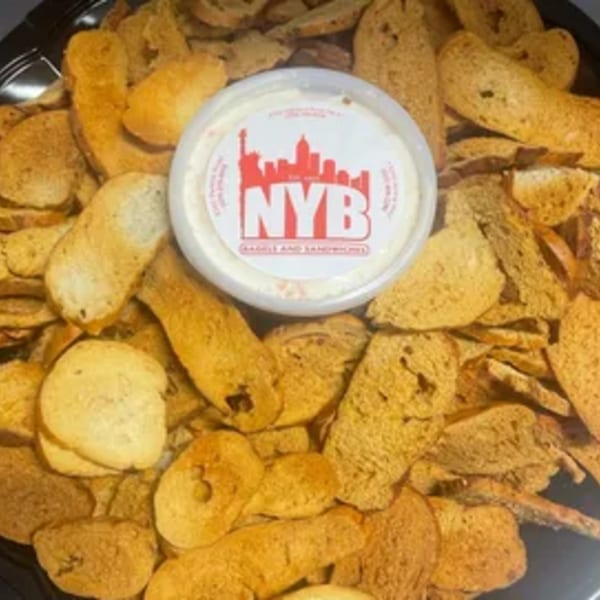A tray of New York Bagel Company bagel chips surrounds a container of cream cheese.