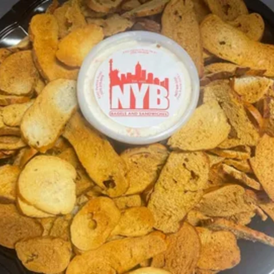 A tray of New York Bagel Company bagel chips surrounds a container of cream cheese.