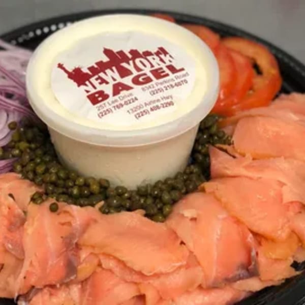 New York Bagel Company cream cheese tub surrounded by smoked salmon, capers, red onions, and tomatoes.